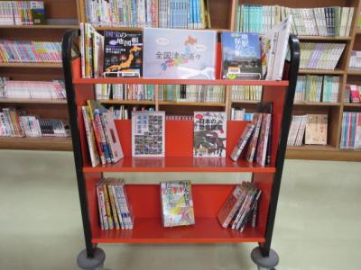 複数の本を乗せたカートの写真。「行こう！　知ろう！　全国津々浦々」と書かれたポスターを掲示しています。