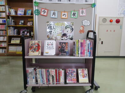 本が載せられたカートの写真。「今月の展示」「偉人に学ぶ」という掲示がされています。