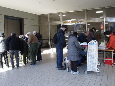 雑誌を乗せたカートの前に並ぶ図書館利用者の方々を写した写真。