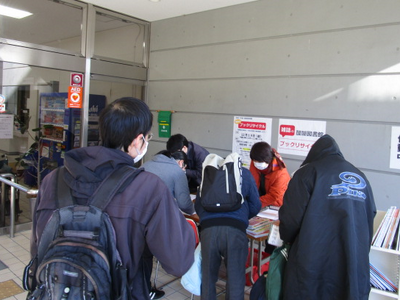 記載台で申込用紙に記入をおこなう図書館利用者の方々を写した写真。