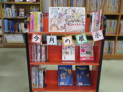 本を載せたカートの写真。「今月の展示」「新しいことにチャレンジ！」という掲示がなされています。