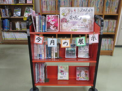 本を載せたカートの写真。「今月の展示」「花のたより」という掲示がなされています。