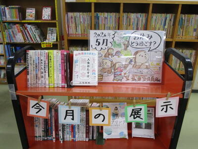 本を載せたカートの写真。「今月の展示」「お休みどう過ごす？」という掲示がなされています。